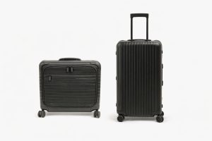 Två svarta Rimowa-väskor, en kabinväska och en större resväska mot vit bakgrund.